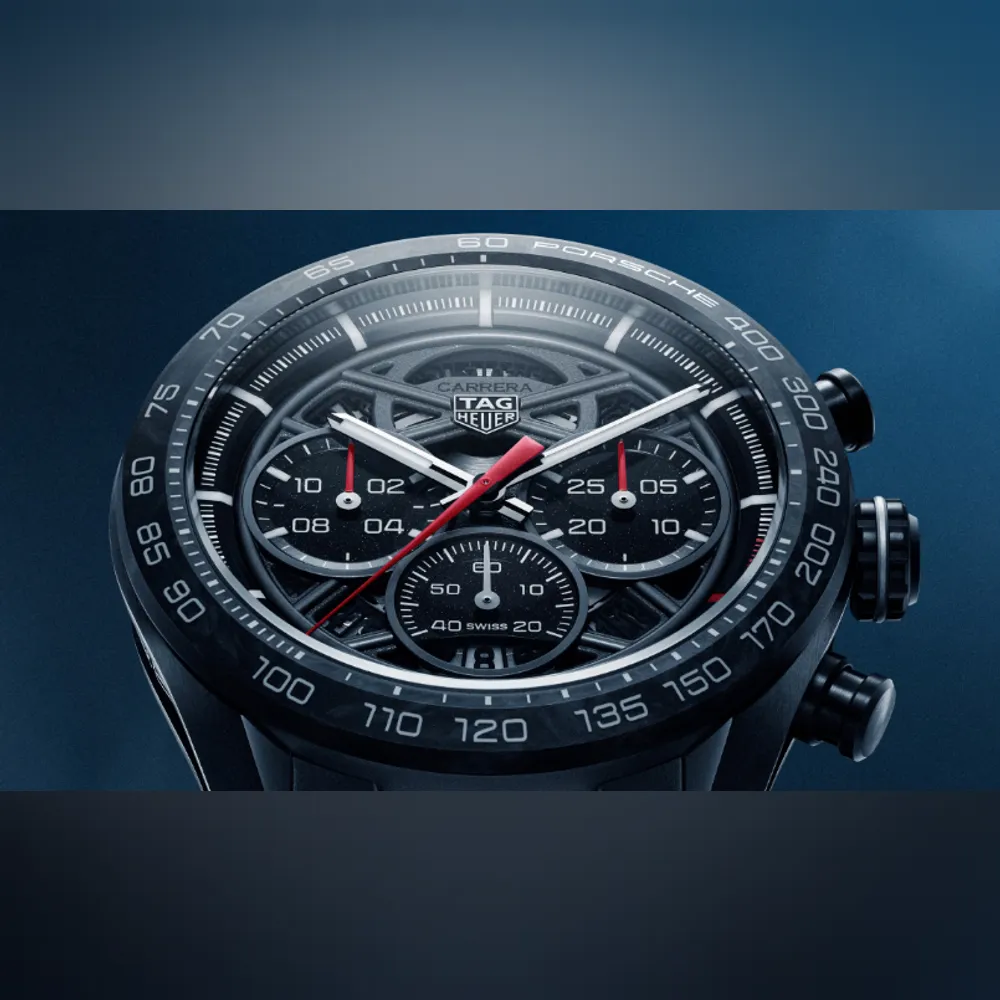 <p>ブラックフォージドカーボンベゼルに白い PORSCHE ロゴ。スケルトンダイヤルはポルシェ963 ハイパーカーのレーシングシャーシを連想させるフォルム。アクセントに赤のマーカー。</p>
